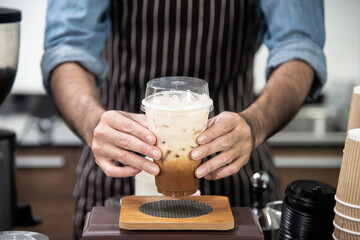 Male barista serve ice latte coffee on coffee bar