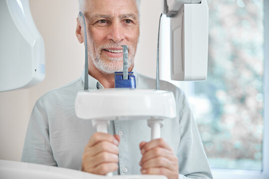 Senior citizen standing by a panoramic x-ray machine