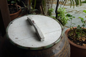 Earthen jar lid made from wood and painted white color in retro style closed water jar, Thailand. In the pass, can see earthen jar lid every house.