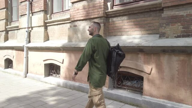 Male backpacker walks along the ancient street enjoying old architecture. Man traveler with backpack