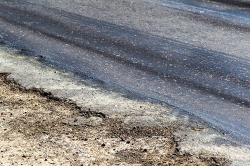 Damaged road, damaged chopped asphalt with potholes and spot. Very bad asphalt road with large...