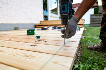 Building site - laying larch floorboards on a terrace. Installing of siberian larch flooring.