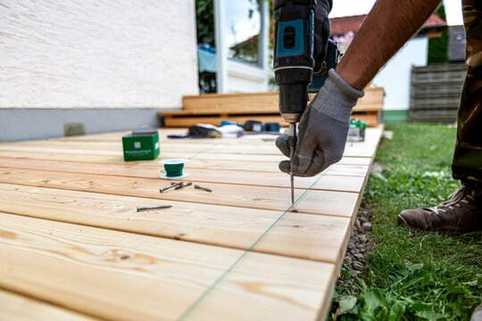 Building site - laying larch floorboards on a terrace. Installing of siberian larch flooring.