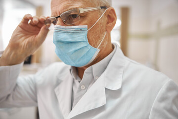 Senior man wearing a mask and glasses working at clinic