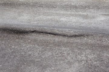 Damaged road, damaged chopped asphalt with potholes and spot. Very bad asphalt road with large trenche. Terrible technology of asphalt production in construction of road. Soft Asphalt melts from heat