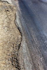 Damaged road, damaged chopped asphalt with potholes and spot. Very bad asphalt road with large trenche. Terrible technology of asphalt production in construction of road. Soft Asphalt melts from heat