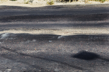Damaged road, damaged chopped asphalt with potholes and spot. Very bad asphalt road with large...