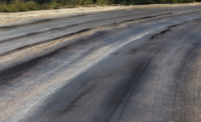 Damaged road, damaged chopped asphalt with potholes and spot. Very bad asphalt road with large...
