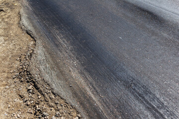 Damaged road, damaged chopped asphalt with potholes and spot. Very bad asphalt road with large trenche. Terrible technology of asphalt production in construction of road. Soft Asphalt melts from heat