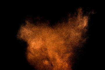 Orange powder explosion on black background. Colored powder cloud. Colorful dust explode. Paint Holi.