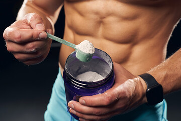 Athletic man holding a container with protein powder - obrazy, fototapety, plakaty