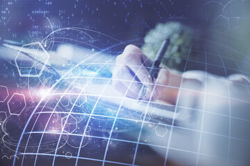 Double exposure of hands making notes with world map hologram and data theme icons. Concept of international network data.