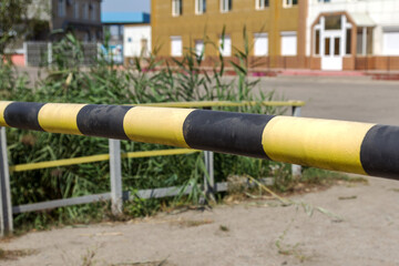 Old and rusty car barrier on the road to the private office area. Iron yellow-black blocking the road to road transport barrier. Barrier of private property