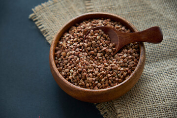 Buckwheat groats in a wooden bowl and vintage scoop. Close up on a black background. copy space for text