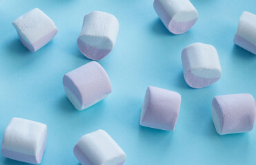 scattering of marshmallows, multi-colored candies, marshmallows, on a flat blue surface. Reflection of the shadow. Sweet life, sugar problems, joy for children, addiction. Holiday sweets, sweet decor,