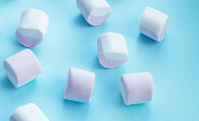 scattering of marshmallows, multi-colored candies, marshmallows, on a flat blue surface. Reflection of the shadow. Sweet life, sugar problems, joy for children, addiction. Holiday sweets, sweet decor,
