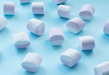 scattering of marshmallows, multi-colored candies, marshmallows, on a flat blue surface. Reflection of the shadow. Sweet life, sugar problems, joy for children, addiction. Holiday sweets, sweet decor,