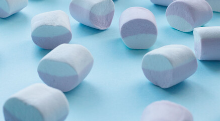 scattering of marshmallows, multi-colored candies, marshmallows, on a flat blue surface. Reflection of the shadow. Sweet life, sugar problems, joy for children, addiction. Holiday sweets, sweet decor,