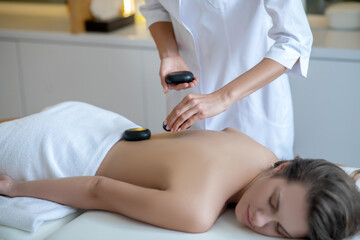Obraz na płótnie Canvas Young woman having stone massage therapy in a salon