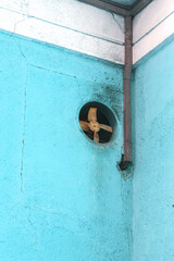Dirty old antique metal fan in the wall of the building. An ancient industrial mechanical iron fan in the circular hole of the building wall