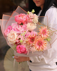 Fresh beautiful flower. Woman holding a big delicate flower bouquet of roses, peony, astilbe and others in pink colors.