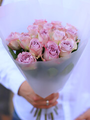 Young man holding a beautiful blossoming flower bouquet of rose. Fresh rose flowers background.