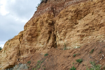 Fototapeta premium Landslide zone on Black Sea coast. Rock of sea rock shell. Zone of natural disasters during rainy season. Large masses of earth slip along slope of hill, destroy houses. Landslide - threat to life