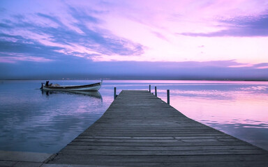 A boat approaches the jetty of the Albufera of Valencia in a sunset