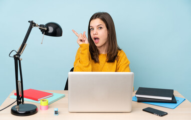 Student girl studying in her house isolated on blue background intending to realizes the solution while lifting a finger up