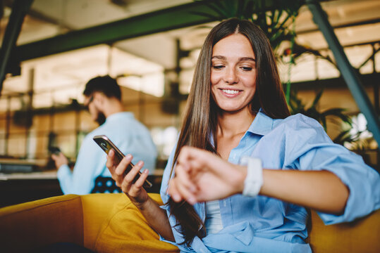 Carefree Caucasian woman 20s checking time on wearable smartwatch during leisure recreation with digital tablet, casual dressed millennial female using modern technology and wrist accessory