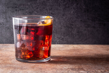 Boulevardier cocktail and orange zest on rusty background.Copy space