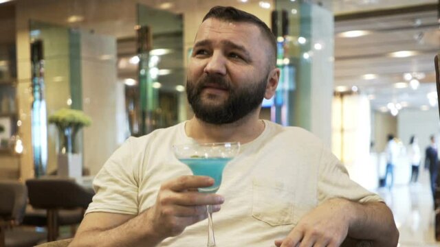 Happy young man drinking beer in hotel bar