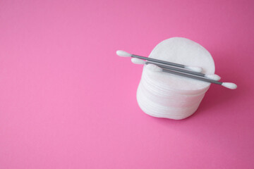Clean cotton buds for cleaning ears and cotton pads for removing make up and washing face on pink background. Personal care and hygiene products concept. Copy space.