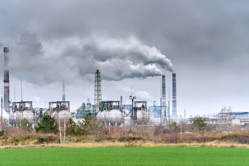 Fototapeta na wymiar View of a chemical plant with Smoking chimneys against a dark cloudy dirty sky