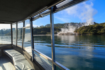 Steam rises from the Orakei Korako geothermal area, New Zealand, seen from an approaching boat 