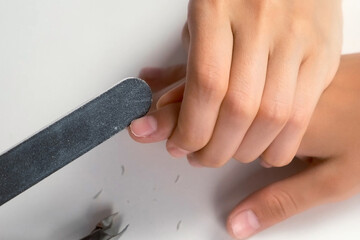 Manicurist master woman is polishing her son's boy nails using file, hands closeup. Mom is doing...