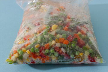 Mix of homemade organic frozen vegetables in a plastic bag: paprika, carrot, green beans, tomato and green pea. Healthy and vegan food.