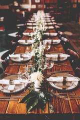 Wedding banquet, serving wooden table with silver plates and decorated with flowers