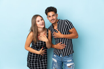 Naklejka premium Teenager caucasian couple isolated on blue background smiling a lot while putting hands on chest