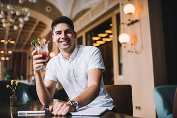 Cheerful man with cocktail in cafe