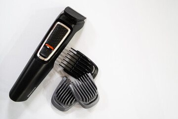 Set of electric hair clippers and attachments for they isolated on white background. Closeup.