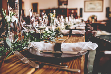 Wedding banquet, serving wooden table with silver plates and decorated with flowers