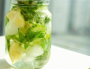 Health care, fitness, healthy nutrition diet concept. Fresh cool lemon cucumber mint infused water, cocktail, detox drink, lemonade in a glass jar.