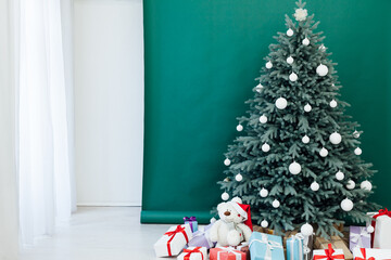 Fototapeta premium Interior with blue Christmas tree with gifts for new year decor winter postcard green background