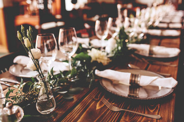 Wedding banquet, serving wooden table with silver plates and decorated with flowers