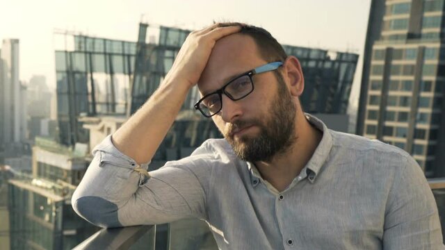 Sad, unhappy lonely man sitting on terrace at luxury rooftop bar
