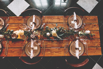 Wedding banquet, serving wooden table with silver plates and decorated with flowers