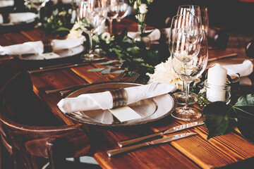 Wedding banquet, serving wooden table with silver plates and decorated with flowers