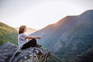 woman doing yoga overlooking the mountain at sunset