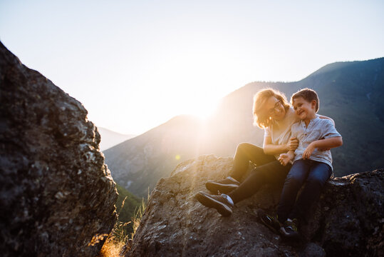 Mother and six-year-old son sitting on the mountain at sunset